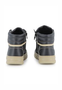 Bottines en cuir noir avec une finition texturée, des accents beige et une fermeture éclair à l'arrière, dotées d'une semelle épaisse de couleur claire.