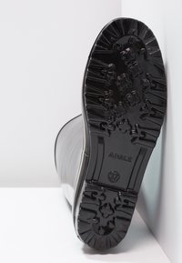 Semelle de bottes en caoutchouc noir avec un design texturé. Présente des bords rainurés et un motif floral pour l'adhérence, étiquetée taille 37 et marque Aigle.