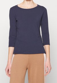 Top blu navy a tre quarti in cotone morbido. Presenta un colletto rotondo e un design aderente, abbinato a pantaloni beige.