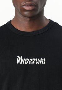Black cotton T-shirt with a round neckline and short sleeves. Features a white stylized logo text "Napapijri" across the chest.