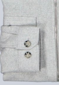 Graue Zip-Jacke aus einem weichen, strukturierten Stoff, mit umgeschlagenen Bündchen und zwei metallischen Knöpfen sowie einem glatten Reißverschluss auf der Vorderseite.