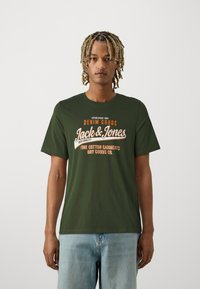 Green cotton T-shirt featuring a white and orange graphic design with the text “Jack & Jones” and a classic crew neckline and short sleeves.