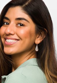 Silver droppörhängen med lager-på-lager spiraldesign. Modellen har långt, mörkt hår och bär en ljusgrön topp. Enkel och elegant look.