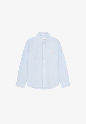 Šviesiai mėlynos ir baltos spalvos dryžuota ilgomis rankovėmis marškiniai. Turi užsegamą apykaklę, priekinę sagų eilutę ir mažą oranžinį emblemos ženklą ant krūtinės.