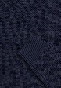 Pullover blu navy in maglia caratterizzato da una texture a coste e un polsino aderente. Il tessuto ha una finitura liscia e un motivo coerente in tutta la superficie.