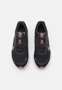 Black athletic shoes with mesh upper, green accents, maroon detailing, and white soles. Features traditional lacing and logo.