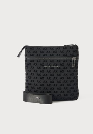 Czarna torba na ramię z nadrukiem "AX" na całej powierzchni, przednia kieszeń na suwak oraz logo "Armani Exchange", pokazana z odpinanym paskiem na jednolitym tle.