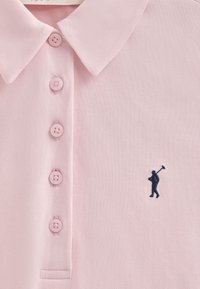 Polo de color rosa claro con tejido texturizado, seis botones rosas y un logo bordado de un golfista en azul marino en el lado izquierdo del pecho.