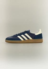 Marineblauwe sneakers met witte strepen en een gestructureerd bovenwerk. Voorzien van een zool van gumrubber en gladde accenten op de hiel en tong.