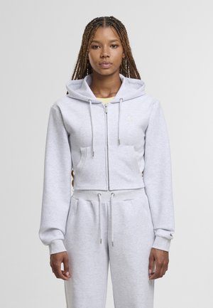 Sweat à capuche court gris avec une fermeture éclair à l'avant, des cordons de serrage et une poche kangourou ; tissu doux et poignets côtelés. Associé à un pantalon assorti.