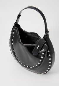 Sac à main noir de forme incurvée, finition brillante, accents cloutés sur le bord et fermeture zippée. Comprend une étiquette détachable.