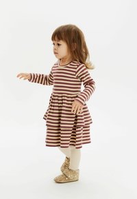 Abito a strisce con maniche lunghe, caratterizzato da colori bordeaux e beige, con una gonna a strati ondulati, abbinato a stivaletti beige con pois e collant crema.