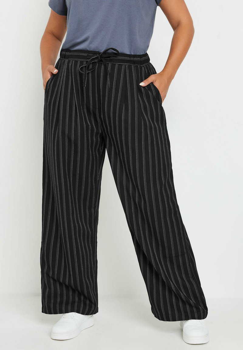 Pantaloni a gamba larga in bianco e nero a righe con vita elastica e cordoncino. Presentano tasche laterali e una vestibilità comoda e morbida.