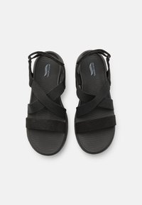 Sandalias negras con diseño de tiras cruzadas, con parte superior sintética y suela de goma texturizada para un buen agarre. Ligeras y ajustables para mayor comodidad.