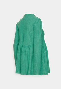 Top verde de manga longa com um design peplum, tecido texturizado e decote franzido. As mangas são franzidas para dar volume.