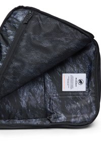 Svart tygpung med dragkedja och nätfack inuti, samt Mammut-logotyp sydd inuti med produktinformation.