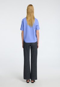 Chemise à manches courtes bleu clair avec une coupe décontractée, assortie à un pantalon large en denim foncé taille haute. Design simple, sans motifs ni accents visibles.