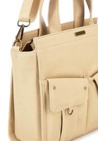 Beżowa torebka materiałowa z skórzanymi akcentami, podwójnymi uchwytami u góry, regulowanym paskiem, kieszenią z przodu, złotymi elementami i wyszywanymi detalami.