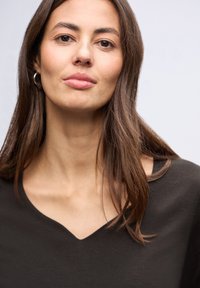 Tmavý top s výstřihem do V vyrobený z hladké látky. Design obsahuje krátké rukávy a volný střih, s jednoduchým a čistým výstřihem.