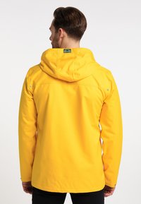 Gul vandtæt jakke med hætte, der har en glat overflade, enkelt design og trykknaplukninger på skuldrene.