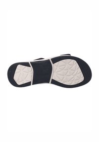 Musta kumipohja, jossa on teksturoitu kuvio ja valkoinen välikerros. Varustettu kolmionmuotoisilla urilla pidon parantamiseksi. Velcro-nauhat näkyvät kengän sivuilla.