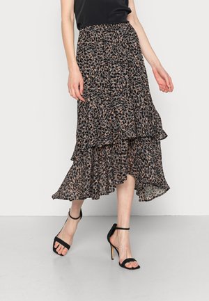 Woman wearing a black sleeveless top and a flowy, multi-layered leopard print midi skirt paired with black high-heeled sandals.