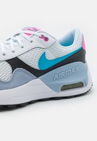 Le sneakers Nike Air Max presentano un accento blu e rosa su una tomaia in rete e suede bianca, con un'unità di ammortizzazione ad aria visibile e una suola testurizzata.