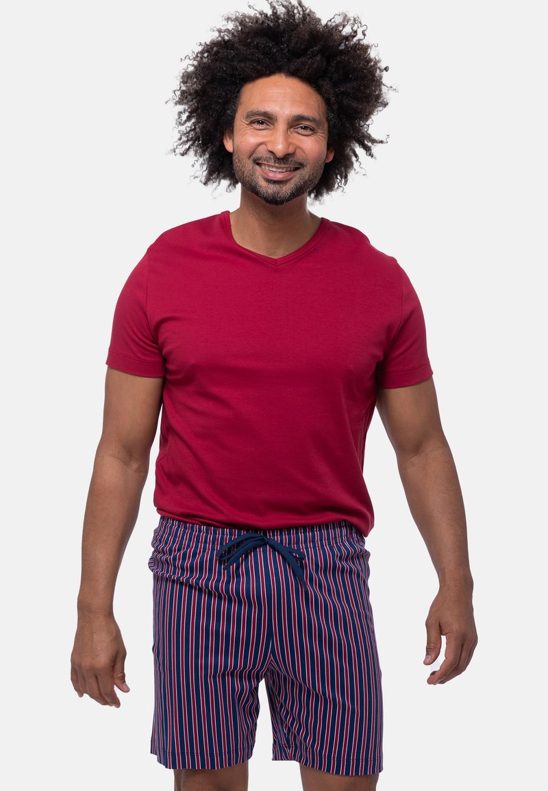 Rød kortærmet V-hals t-shirt parret med navy og rød vertikalt stribede badebukser med elastisk talje og snørre.