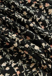 Tissu noir avec un motif floral composé de petites fleurs roses et crème, présenté en plis doux et froissés, mettant en avant la texture.