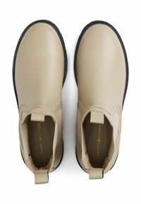 Botines beige de cuero suave, con paneles laterales elásticos, punta redonda y suelas de goma negra en contraste.