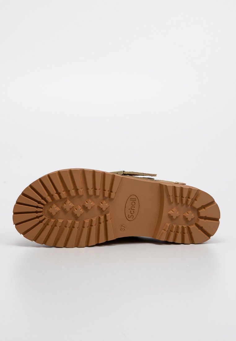 Semelle d'une chaussure à semelle en caoutchouc marron avec un motif de semelle profond, marque "Scholl", et la taille numéro 37 visible.