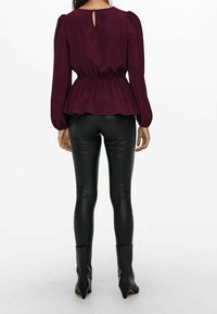Burgundy peplumtop med långa puffärmar och detalj med nyckelhål bak, kombinerat med svarta imitationläderleggings och ankelstövlar.