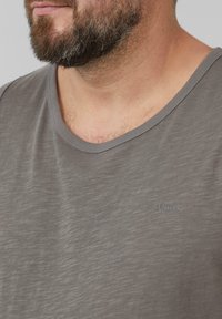 Grijze, T-shirt met korte mouwen en een gladde textuur. Heeft een ronde halslijn en een klein "s.Oliver" logo op de linkerkant van de borst.