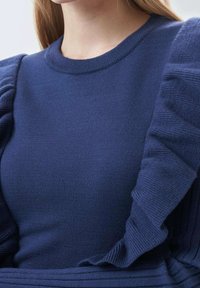 Maglione blu navy con texture a coste e maniche arricciate, dotato di un classico colletto a giro e una vestibilità aderente. Adatto per un look casual.