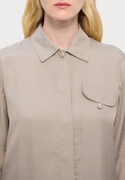 Light beige button-up shirt with thin vertical stripes, classic collar, and a single chest pocket with a button closure. Soft fabric.