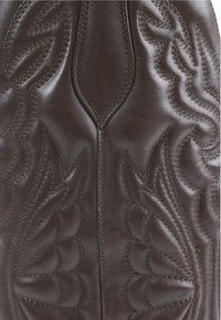 Borsa in pelle marrone con design ad impressione a forma di ali e cuciture a contrasto. Texture liscia con una forma ben definita e estremità affusolate.