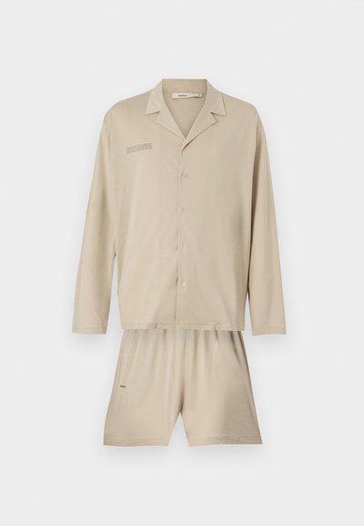 Lys beige pyjamasæt bestående af en langærmet skjorte med knapper og brysttryk samt matchende shorts med elastisk talje.