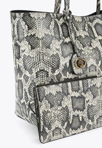 Torebka typu tote w czarno-białym wzorze wężowej skóry, wykonana z teksturowanej sztucznej skóry, z dekoracyjnym okrągłym detalem metalowym oraz odpinaną saszetką.