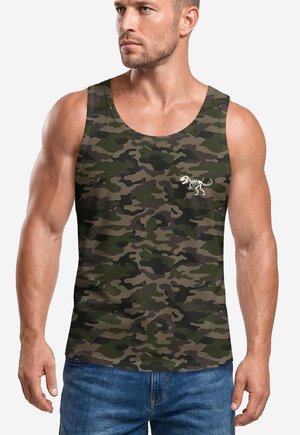 Muscular man wearing a green and brown camouflage tank top with a small white dinosaur skeleton design on the chest, paired with blue jeans.
