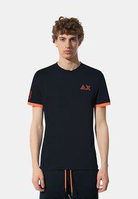 T-shirt nera a maniche corte con accenti arancioni sulle maniche e sul logo. Realizzata in tessuto morbido con scollatura a girocollo.