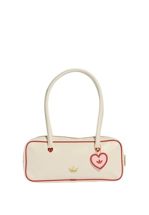 Borsa a mano rettangolare color crema con bordatura rossa, logo Adidas dorato e un ciondolo a forma di cuore rosso e rosa appeso a una delle maniglie.