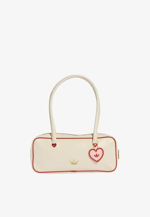 Borsa a mano rettangolare color crema con bordatura rossa, logo Adidas dorato e un ciondolo a forma di cuore rosso e rosa appeso a una delle maniglie.