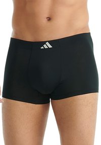 Svarta boxershorts tillverkade av mjukt material, med en åtsittande passform och en silverfärgad Adidas-logotyp på midjebandet. Slät textur, minimalistisk design.