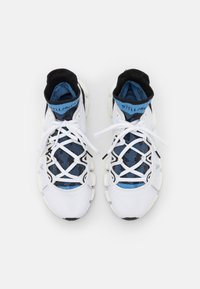 Baskets de course blanches avec un dessus en maille texturée, un col noir et des accents bleus. Elles disposent d'un système de laçage unique et d'une semelle en caoutchouc épaisse.