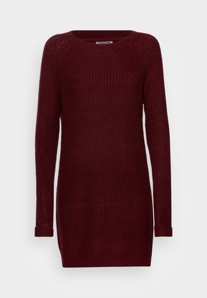 Robe-pull bordeaux à manches longues en tricot, avec un col rond et des poignets côtelés, présentée sur un fond clair uni.