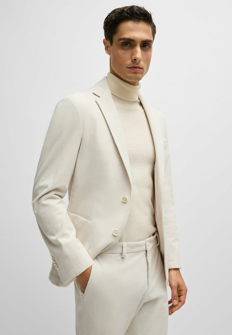 Beige gestreepte blazer met twee knopen, smalle revers en zijzakken, gecombineerd met een bijpassende coltrui. Gladde textuur.