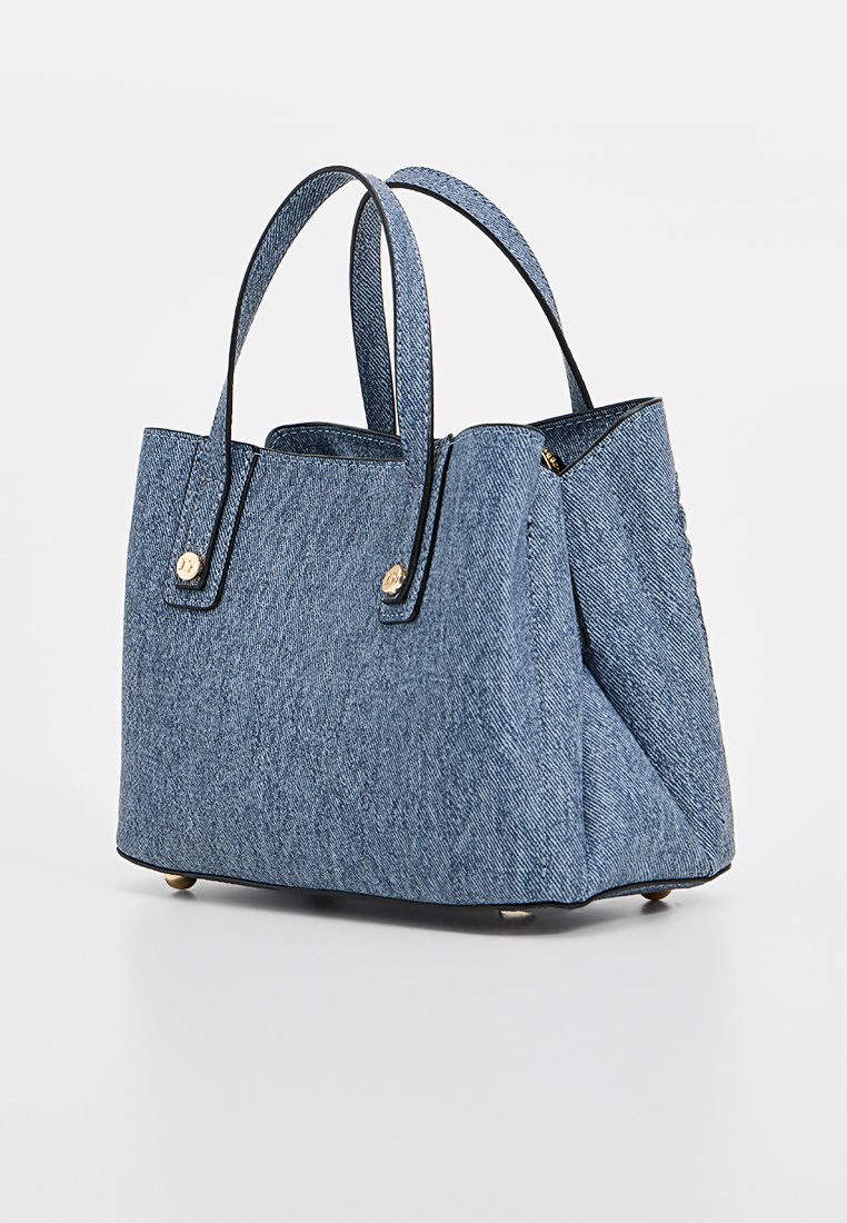 Sac en denim avec deux poignées, en tissu bleu texturé, accents en métal doré et un design structuré comprenant un fond plat et des coutures latérales.