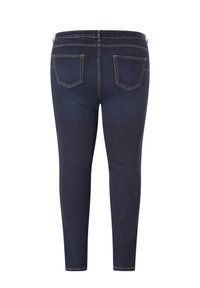 Donkerblauwe denim jeans met een slim fit, voorzien van twee achterzakken en contrasterende gele stiksels langs de naden. Soepele textuur.