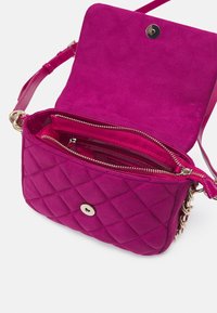 Borsa a tracolla in suede fucsia con motivo trapuntato, chiusura a scatto magnetico e scomparti con zip. Presenta elementi in metallo argentato e dettagli con catena.