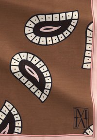 Brązowy materiał z czarno-białymi wzorami przypominającymi paisley oraz różową bordiurą, z czarnym logo "M" w rogu.